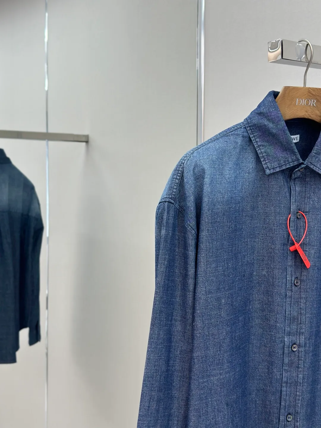 P430 Loewe Anagram Gradient Embroidered Pocket Shirt Made of custom-made high-quality cotton chambray fabric, with a unique washed gradient blue as the main tone, from dark to light and from thick to light. The chest patch pocket is decorated with Loewe Anagram embroidery as its soul, engraved with LOEWE-style casual elegance, and the natural and smooth lines show the casualness.  Imported embroidery machines are used, and advanced computer control systems and precision mechanical components are used to realize Loewe embroidery operations.  The gradient dynamic spray dyeing process uses specialized spray dyeing equipment to accurately spray dye onto the surface of the fabric in the form of mist (by accurately controlling the different dimensions of the spray of the spray dyeing equipment, combined with the movement speed and direction during the dyeing process) to present a smooth and natural transition effect of color. The butterfly rhyme pinch pleating body dart technology is inspired by the beautiful shape of butterflies, and uses precise pinch pleating techniques to create a flexible pleat effect like butterfly wings on the garment, making the garment fit more closely to the body.  size:44.46.48.50